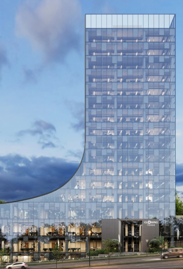 Exterior view of the Glowing Tower building in Prishtina, showing the full structure with surrounding roads and trees.